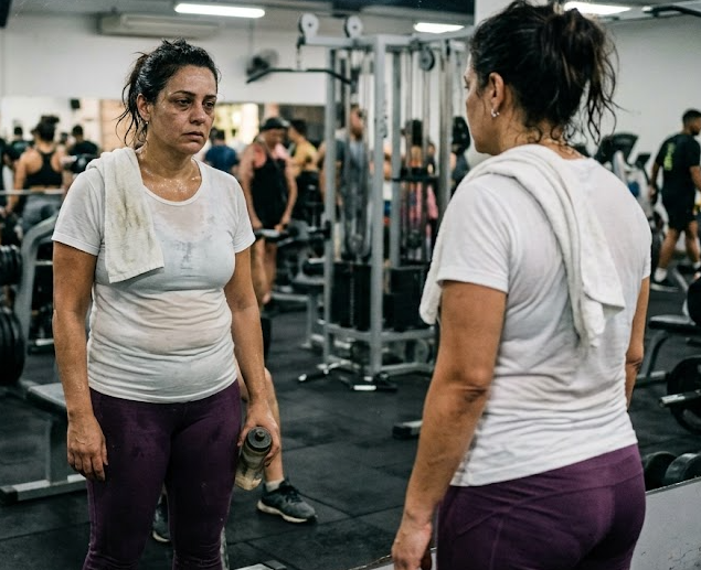 Mulher se olhando no espelho na academia